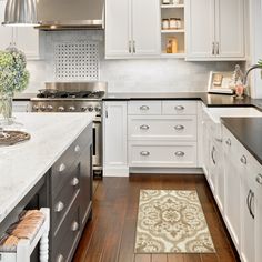 a kitchen with white cabinets and black counter tops, an area rug on the floor