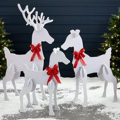 three white reindeer statues with red bows on them