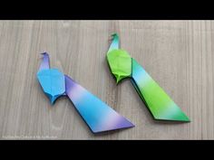 two origami birds sitting on top of a wooden table