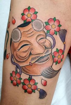 a tattoo on the leg of a person with flowers and an image of a laughing buddha