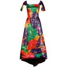 Incredible vintage metallic lame dress by Arnold Scaasi with a high low hemline and open back with chain detail. Petal shaped flap sleeves and tropical-inspired floral printed colorful silk fabric. Fully lined with rear zip and hook closure. Hidden side pockets. Fits like a modern size medium-large. The bust measures 38", waist 29.75", hips 46" and the total length 57" with a high low hem. Excellent vintage condition with no noted flaws. Made in USA. Arnold Scaasi, Off The Shoulder Evening Dress, 1970s Clothing, Lame Dress, Silk Evening Gown, Off Shoulder Evening Dress, Satin Evening Dresses, Evening Gown Dresses, Mesh Maxi Dress