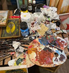 an artist's easel with paint, brushes and other art supplies on it