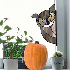 a pumpkin sitting on top of a window sill next to a potted plant