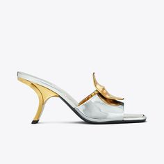 Our Patos sandal is defined by mismatched metal discs, evocative of ’60s glamour. Crafted in metallic leather, the sculptural silhouette features a slanted heel that gives it a chic, distorted look. A cushioned insole ensures day-to-night comfort. 60s Glamour, Tory Burch Heels, Heeled Mule, Plastic Heels, Mule Sandals, Footwear Design Women, Designer Sandals, Metallic Leather, Leather Ankle Boots