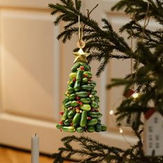 a green christmas tree ornament hanging from a pine tree