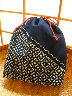 a blue bag sitting on top of a bamboo basket next to a window with red string