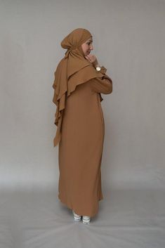 Introducing the Avalom Prayer Gown Umrah Abaya Dress in Brown by Annah Hariri, the perfect addition to your modest wardrobe. This elegant one-piece abaya dress is made from non-wrinkling fabric, ensuring that you always look put-together without the hassle of ironing.Featuring a classic A-cut design, this abaya dress offers ample coverage, making it suitable for any prayer occasion. It also comes with pockets, making it functional and convenient for carrying your essentials. The beautiful sleeve Umrah Abaya, Modest Wardrobe, Abaya Designs, Abaya Dress, Modest Wear, Cuff Detail, Niqab, Cut Design, Wrinkle Free