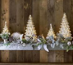 three small christmas trees sitting on top of a table next to candles and other decorations