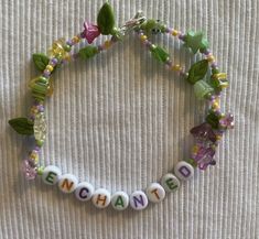 a beaded name bracelet with flowers and leaves on the beads that spell enchant