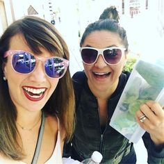 two women are posing for the camera with sunglasses on and one is holding a passport