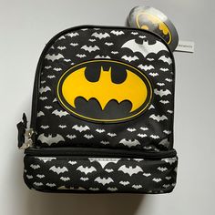 a batman backpack with the logo on it and two balls hanging from it's back