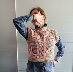 a woman is wearing a crocheted sweater and holding her hands to her face