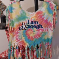 a tie - dyed shirt with the words i am enough on it and tassels