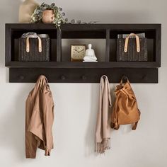 a coat rack with three baskets and two coats hanging on it's sides next to a clock