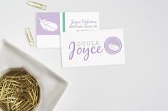 a white plate topped with lots of gold colored paper clips next to a business card