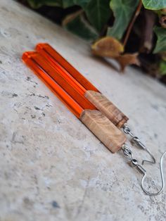 an orange pair of scissors sitting on top of a white counter next to a plant