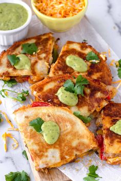 several quesadillas with guacamole and cheese on a cutting board