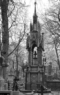 a black and white photo of a cemetery with an old clock tower in the middle