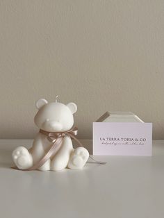 a small white teddy bear sitting next to a card