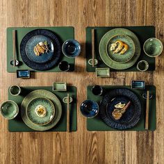 the table is set with plates and silverware on green placemats, which are placed next to each other