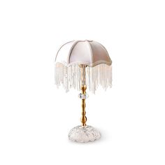 a table lamp with a white and gold shade on it's base, sitting on a white surface