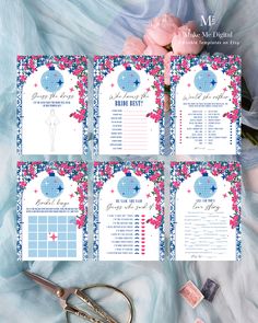 wedding seating cards with pink flowers and blue accents on them, sitting next to a pair of scissor scissors