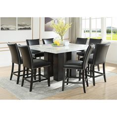 a dining room table with black chairs and a white marble top centerpiece in front of a window