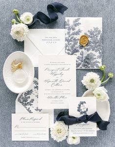 the wedding stationery is laid out with white flowers and blue ribbon, which are tied together