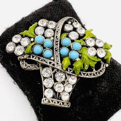 Gorgeous vintage Art Deco blue glass cabochon and rhinestone basket brooch. Ornate filigree pot metal with lovely enameled green leaves and set with turquoise blue glass cabochons and clear rhinestones in a flower basket design. Gorgeous!! In excellent vintage/antique condition with minimal age appropriate wear. No enamel loss. Completely intact. Has secure rollover clasp. Measures 2 1/8 inches tall by 2 1/2 inches Deco Blue, Basket Design, Rhinestone Flower, Vintage Antique Jewelry, Brooch Vintage, Flower Basket, Clear Rhinestones, Vintage Art Deco, Vintage Brooches