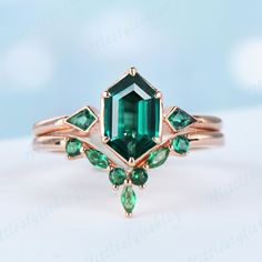 an emerald colored ring is shown on a white surface, with green stones around it