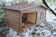 a dog house with a stuffed animal in it's lap and snow on the ground