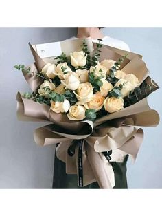 a bouquet of white roses wrapped in brown paper