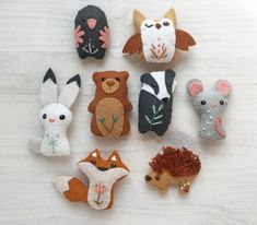 there are many small felt animals on the table together, including one with an animal face