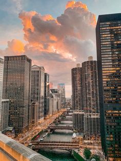 the city skyline is lit up at sunset with clouds in the sky and water below