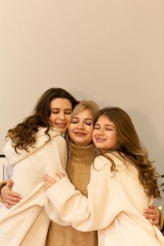 three women wrapped in blankets hugging each other