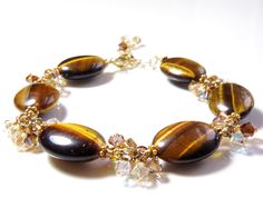 Autumn inspired chocolate brown artisan gemstone bracelet is a gorgeous accessory for the fall season. Handmade with genuine tigers eye gemstones and accented with beautiful Swarovski crystals in champagne, brown and mocha hues. Handmade with 14k gold filled chain, wire and clasp. A rare find for a woman who love artisan gifts with a little sparkle and artisan flare. A great gift for a bridal party for an autumn inspired wedding. Bracelet Details: - Bracelet is 8 inches long plus a 1 inch extend Fall Wedding Jewelry, Tigers Eye Bracelet, Autumn Bracelet, Bridal Party Jewelry, Wedding Bride Jewelry, Brown Jewelry, Handmade Fine Jewelry, Tiger Eye Bracelet, Tigers Eye Gemstone