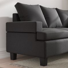 a gray couch sitting on top of a wooden floor next to a white wall in a living room