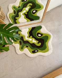 two rugs with green and black designs are on the floor next to a potted plant