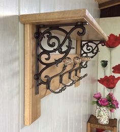 a wooden shelf with metal brackets on it and flowers in vases next to it