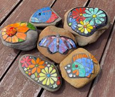 several painted rocks sitting on top of a wooden table next to each other with flowers