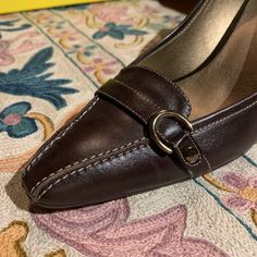 These Gorgeous Joan & David Dark Brown Leather Pumps Have Exquisite Contrast Stitching And A Fun Buckle Detail On The Toe- It Hints At A Sensible Loafer But The Eye Follows The Stitching To The Sexy Curvy Heel. They Have J&D Circa365 Technology Inside So They Are Beautiful And Comfortable! With A Glint Of Woodtone At The Heel- They’ll Look Great With A Sexy Dress For A Night On The Town Or With Jeans For Fall... Never Worn! Genuine Leather 3 Inch Heel Made In Italy For An American-Owned Company Brown Heels With Buckle Closure For Office, Brown Leather Court Shoes For Work, Classic Leather Court Shoes With Buckle Closure, Brown Court Shoes For Formal Spring Occasions, Leather Closed Toe Court Shoes With Buckle, Leather Court Shoes With Removable Insole, Leather Evening Court Shoes With Buckle Closure, Fitted Leather Court Shoes With Removable Insole, Leather Court Shoes With Buckle Closure For Evening