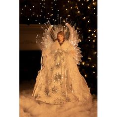 an angel figurine is sitting in the snow next to a christmas tree with lights