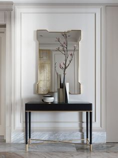 a black table with vases and flowers on it in front of a white wall