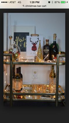 a bar cart with bottles and glasses on it in front of a christmas card display