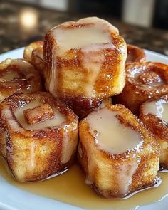 a white plate topped with cinnamon rolls covered in icing