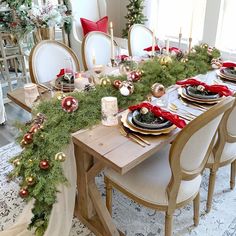 a dining room table set for christmas with candles and greenery on the table top