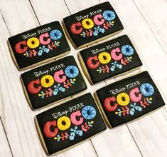 six decorated cookies sitting on top of a white table