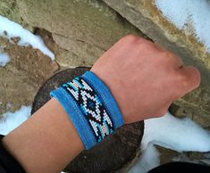 Loom Beaded Cuff Bracelet with Native American Style pattern in blue, white, turquoise, black and beige colors designed by me. The beaded part of the bracelet is sewn on a double-layered blue-jeans-material. Made out of Czech seed beads, 100% cotton jeans material and a metal button clasp.    This bracelet measures 18 cm or 7 inches and is 4,5 cm or 1,77 inches wide.  Color and size can be changed up to order! When ordering, please write me a short message about your wrist circumference. Please Blue Wrap Bracelet With Colorful Beads For Festivals, Blue Beaded Bracelets For Festival, Blue Beaded Cuff Bangle Bracelet, Blue Beaded Bangle Cuff Bracelet, Festival Wrap Bracelet With Colorful Beads, Festival Blue Wrap Bracelet With Colorful Beads, Bohemian Blue Cuff Bracelet With Colorful Beads, Adjustable Blue Wristlet Bracelet, Adjustable Blue Beaded Wristband