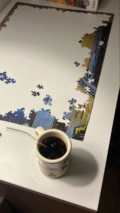 a cup of coffee sitting on top of a table next to a puzzle piece wall