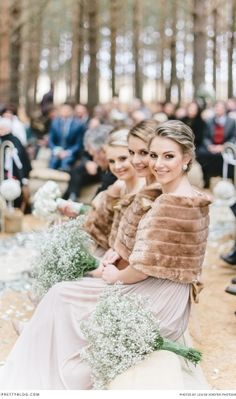 two beautiful women sitting next to each other in front of a large group of people